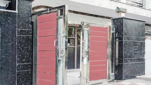 A building entrance with a red door, a checkered floor, and a black marble pillar.