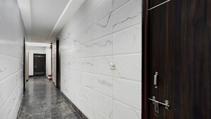 A hallway with white marble walls and a dark wooden door.