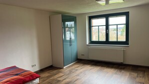 Una habitación con cama, armario, ventana con vistas y radiador.