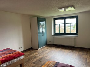 A room with a bed, a wardrobe, a window with a view, and a radiator.