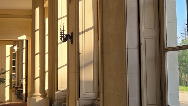 A corridor with columns, benches, and a chandelier. - Bed and breakfast at Château de Craon Swimming pool, tennis court, park Pdj included. (Craon)