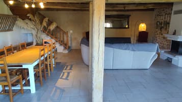 Un intérieur rustique avec une table à manger en bois, des chaises, un canapé et une cheminée.
