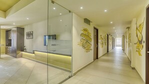 En modern hotellkorridor med en receptionsdisk, glasväggar och dekorativ väggkonst.