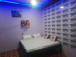 A bedroom with a bed, pillows, a wall with repeated text, and a ceiling light.