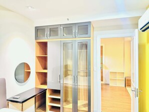 Quarto moderno com escrivaninha, guarda-roupa com portas de vidro e espelho.