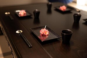 A table with black plates, chopsticks, and cups, some with pink flowers. - OyadoKinokuniyaSakaemachi (Nagasaki)