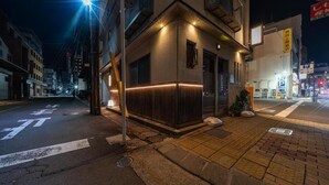A street view at night with a building featuring a lit entrance and a visible sign. - OyadoKinokuniyaSakaemachi (Nagasaki)