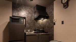 A compact kitchen with a microwave, stove, and trash bins. - OyadoKinokuniyaSakaemachi (Nagasaki)