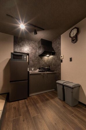 Una cocina compacta con microondas, estufa y botes de basura.