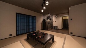 A room with tatami flooring, a dark wooden table with red objects, and a traditional sliding door. - OyadoKinokuniyaSakaemachi (Nagasaki)