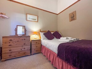 A bedroom with a wooden dresser, a bedside table with a lamp, a bed with a purple blanket, and two wall-mounted pictures. - 1 bedroom accommodation in Snettisham (Snettisham)