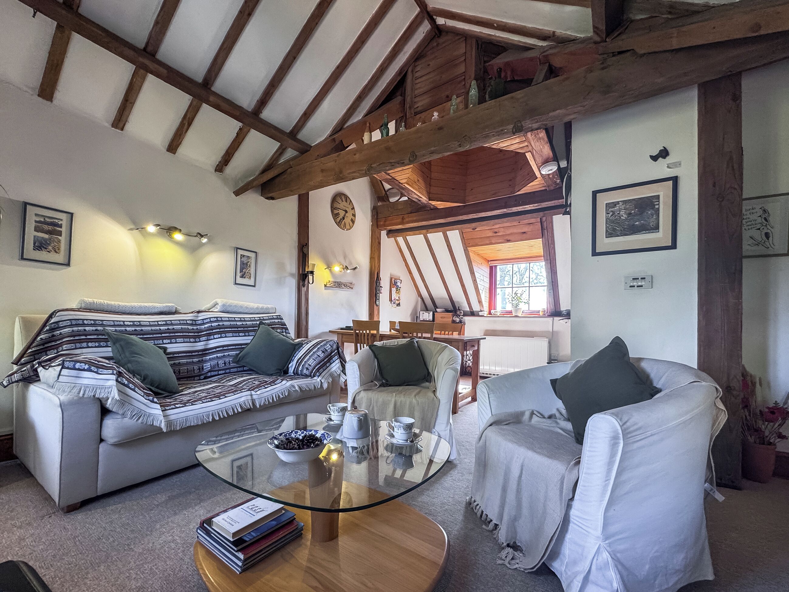 A cozy living room with a sofa, armchair, and a glass coffee table.