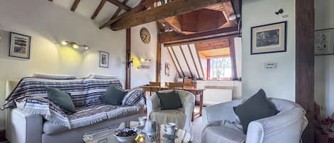 Una sala acogedora con un sofá, un sillón y una mesa de centro de vidrio.