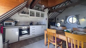 Uma cozinha com armários brancos, micro-ondas, forno e uma mesa de jantar com cadeiras.