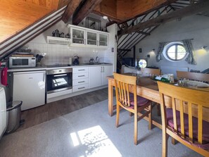 A kitchen with white cabinets, a microwave, an oven, and a dining table with chairs. - 1 bedroom accommodation in Snettisham (Snettisham)