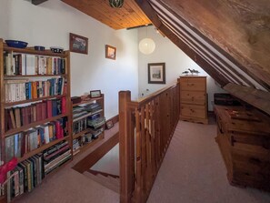 A wooden staircase leading to an upper level with a bookshelf filled with books and a wooden dresser. - 1 bedroom accommodation in Snettisham (Snettisham)