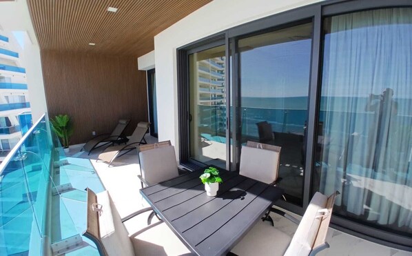 A balcony with a table, chairs, and a potted plant.