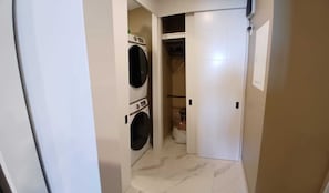 Uma lavanderia com duas máquinas de lavar e uma porta fechada.
