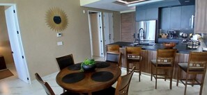 A modern kitchen with a central island, a dining area with a round table and chairs, and a sunburst wall decoration.
