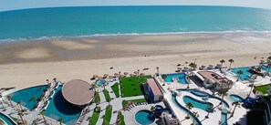 Un resort con varias piscinas, una playa y vistas al océano.