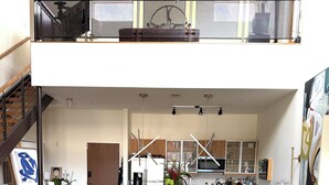 Ein modernes Wohnzimmer mit einer Couch, einem Couchtisch und Büchern. Eine Treppe führt zu einer oberen Ebene.