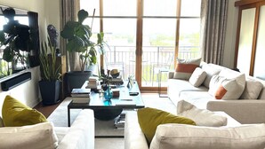 Ein Wohnzimmer mit einer Sofagarnitur, einem Couchtisch, einem Fernseher und einem Deckenventilator.