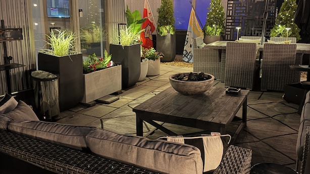 Eine Terrasse im Freien mit Korbmöbeln, Blumentöpfen und einer Flagge.