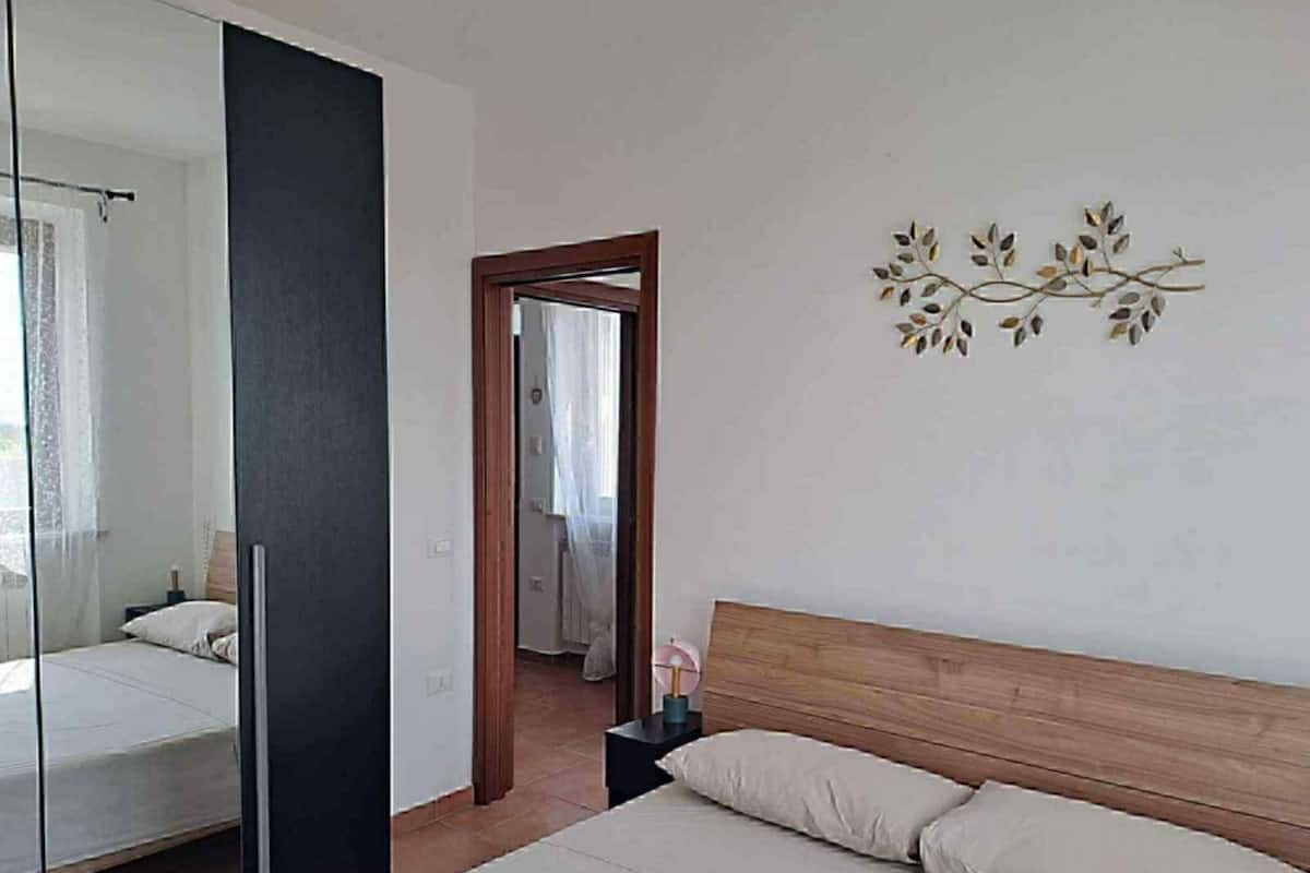 Une chambre à coucher comprenant un lit, une table de chevet, un miroir et un élément décoratif mural.