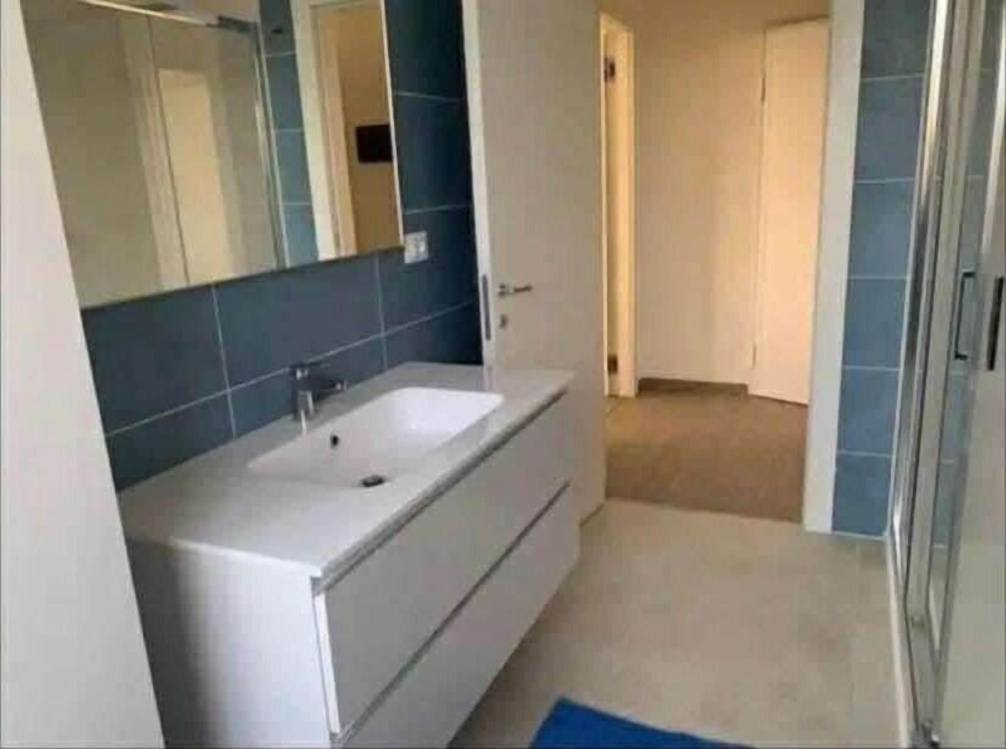 Un baño con un lavabo blanco, un espejo y azulejos azules.