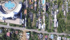 Vue aérienne d’une zone côtière avec un grand bâtiment circulaire, qui pourrait être un hôtel, et qui comprend une piscine centrale.