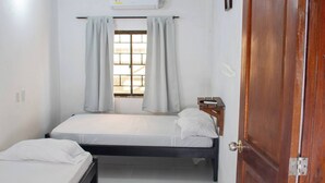 Une chambre avec deux lits, une fenêtre avec des rideaux, un climatiseur et une porte en bois portant le numéro 2.