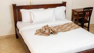A single bed with a wooden frame, white bedding, and a brown blanket.