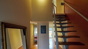 Eine moderne Treppe führt zu einer oberen Etage. Ein gerahmtes Bild hängt an der Wand oben.