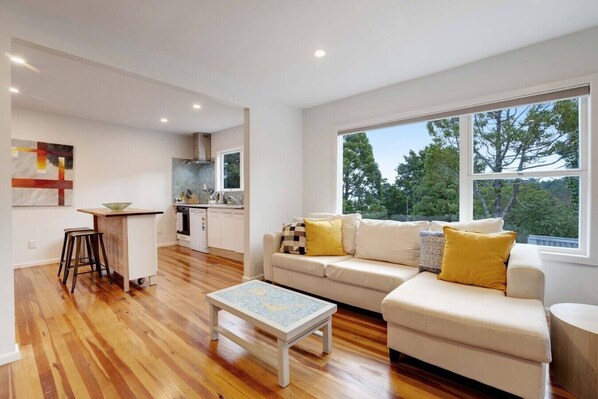 A modern living room with a sofa, coffee table, and a view of the outdoors.