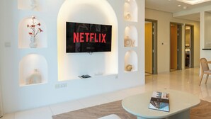 A modern living room with a large TV mounted on the wall, a coffee table, and decorative shelves with vases. - Paramount Luxury 2BR-Burj Khalifa Views (Dubai)