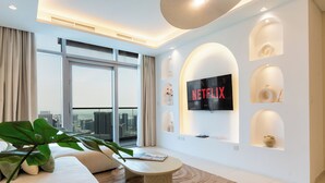 A modern living room with a large TV, a sofa, a coffee table, and a view of the city. - Paramount Luxury 2BR-Burj Khalifa Views (Dubai)