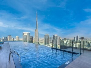 A rooftop infinity pool with a city skyline view, including a prominent skyscraper.