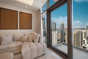 A modern living room with a sofa, a round table, and large windows offering a city view.