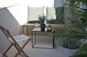 A balcony with a wooden chair, a small table with a glass, and potted plants. - The Habitus Project (Kerkira)