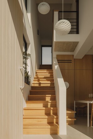 A modern interior with a wooden staircase, white walls, and a dining area. - The Habitus Project (Kerkira)