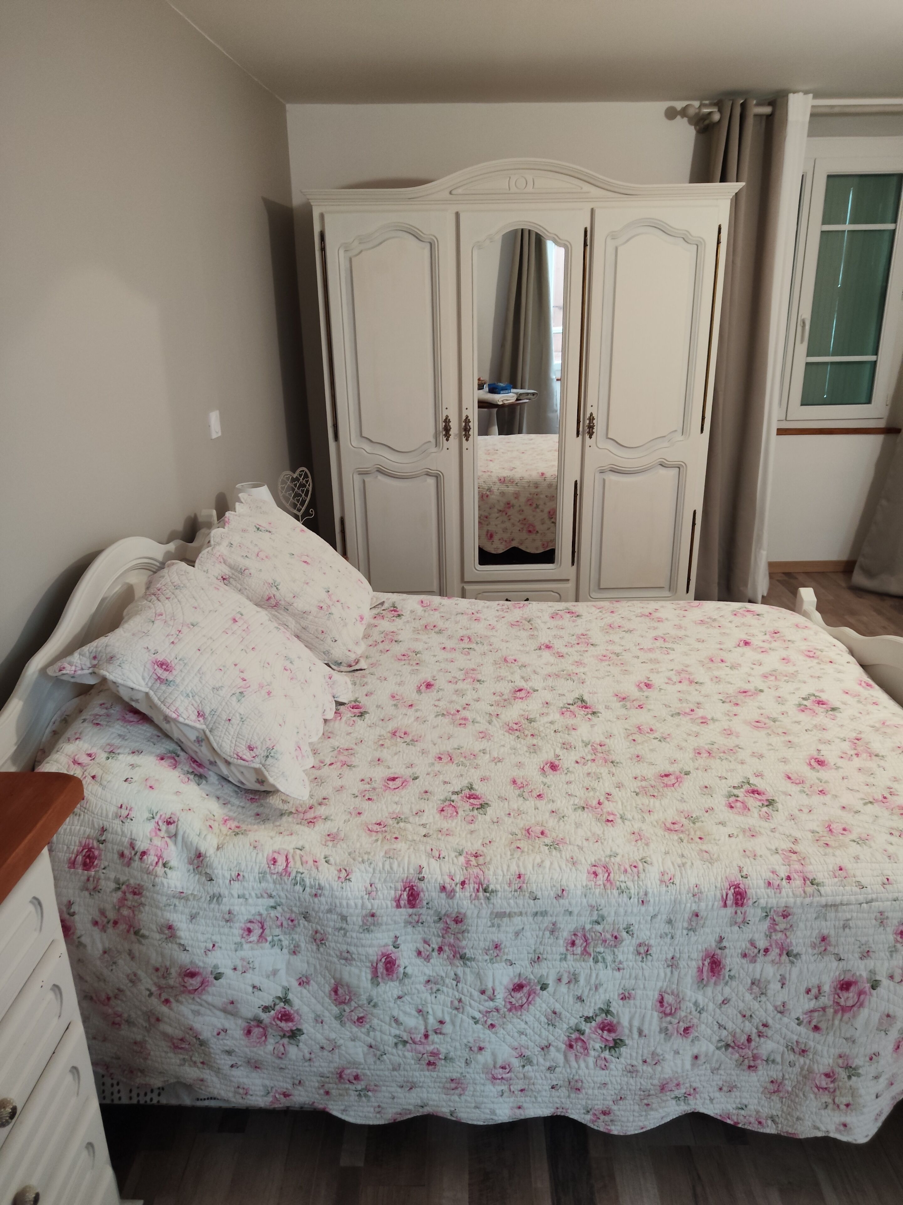 A bedroom with a bed, a wardrobe, and a mirror.