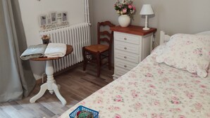 Une chambre à coucher comprenant un lit, un bureau, une chaise, une commode et un radiateur.