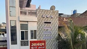 A modern building with a stone facade, multiple windows, and a signboard. - Anandam Homestay (Ujjain)