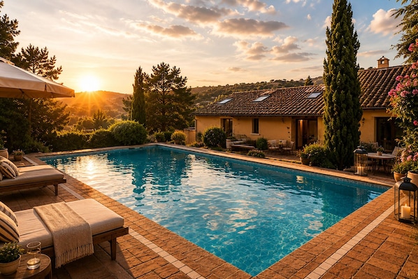 A swimming pool with lounge chairs, a patio area, and a building with a tiled roof.