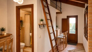 A kitchen with a wooden table and chairs, a staircase, and a view of the outdoors.