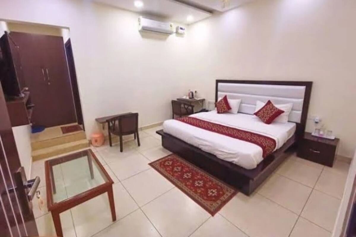 Quarto com cama, mesa de cabeceira, escrivaninha, cadeira e porta.