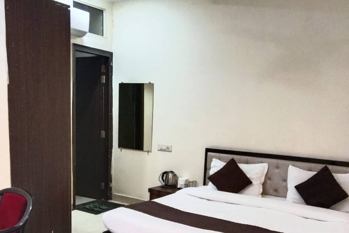 Quarto com cama, cadeira, mesa de cabeceira, espelho e porta.