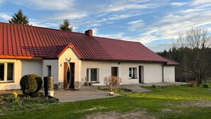 A two-story house with a red-tiled roof, a front door, and a small porch. - Cozy forest house / Przytulna Chatka w Lesie (Mątki)