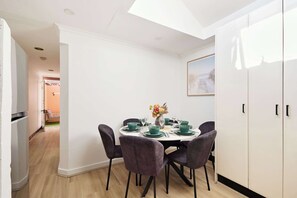 A dining area with a round table, chairs, and a vase of flowers. - Harris St Apt | 5 Mins to Darling Harbour & CBD (Pyrmont)
