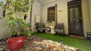 A courtyard with a potted plant, two chairs, a small table, and a door with a 'Welcome' mat. - Harris St House | 5 Mins to Darling Harbour & CBD (Pyrmont)